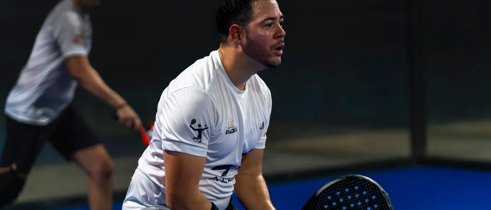 Padelspeler klaar voor de return op een blauwe binnenbaan